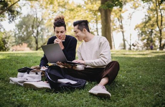 两个学生在草坪上玩电脑
