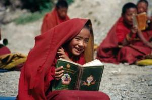 一个微笑的男孩读佛经的照片