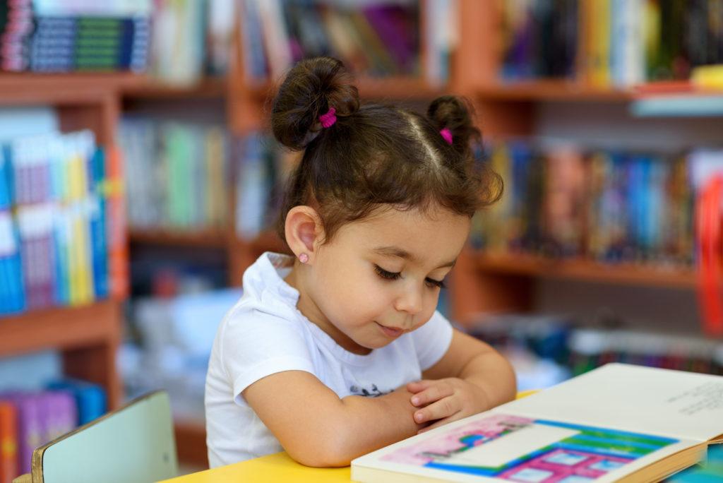 一个小女孩坐在教室的桌子旁看书.