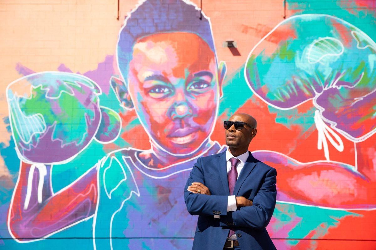 密歇根州立大学丹佛分校校友埃里克·威廉姆斯站在街头艺术前，一个男孩戴着拳击手套.