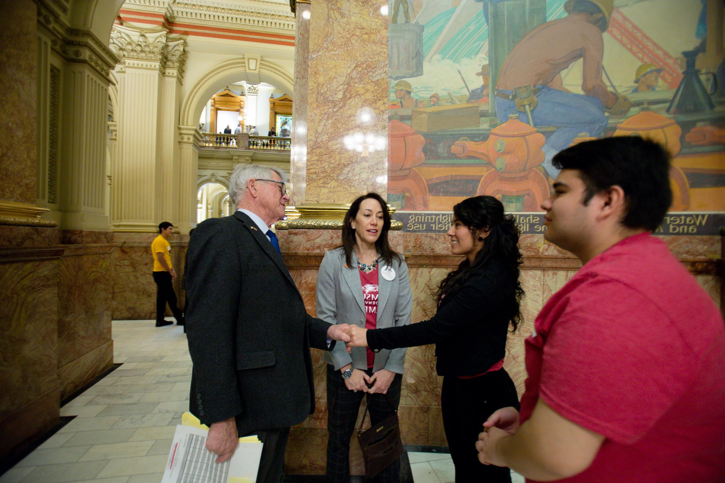 一名女学生在州议会大厦内与一名政客握手.