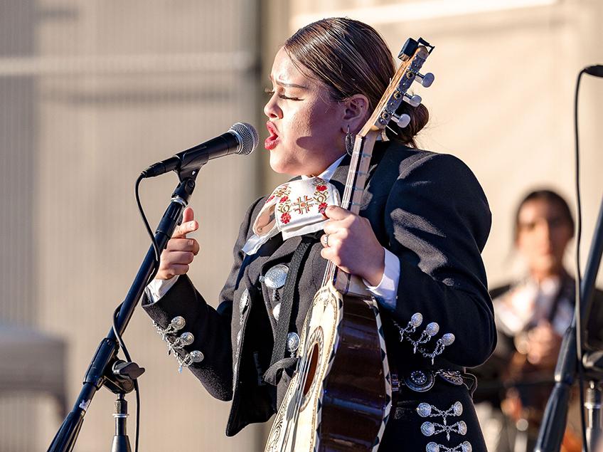mariachi singer holding guitar and singing in microphone
