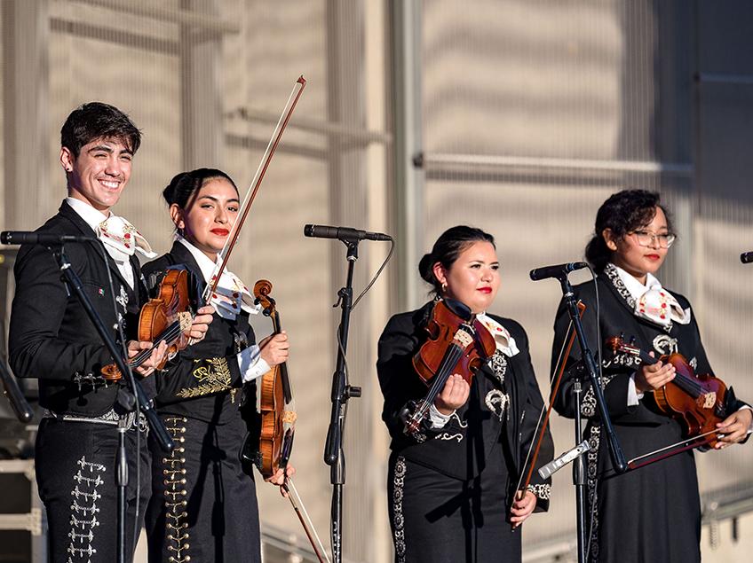 Four mariachi players on a stage