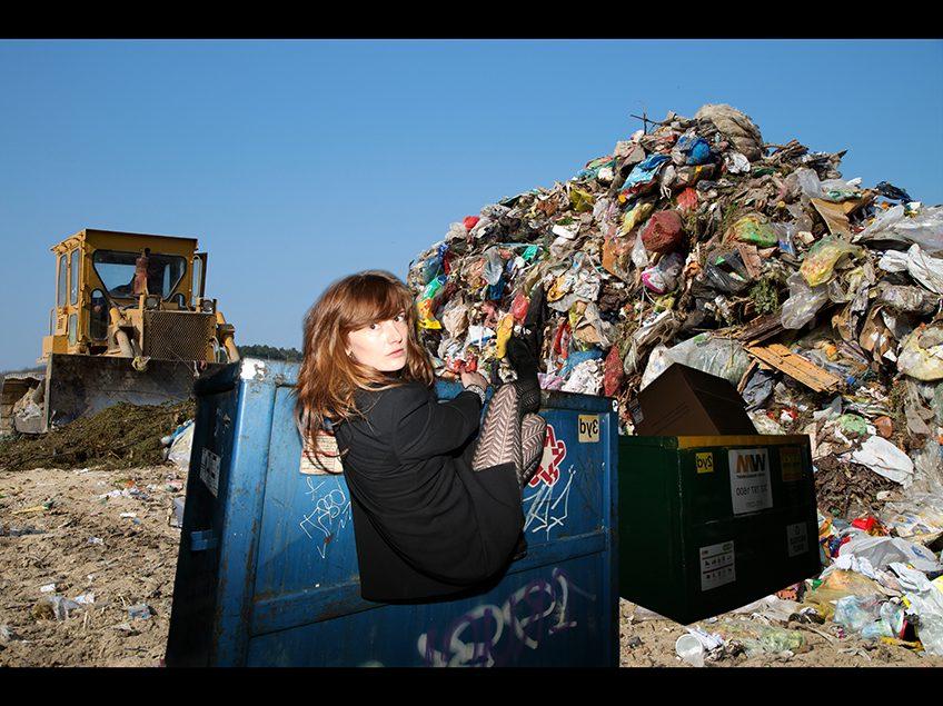 一堆垃圾和一个吊在垃圾箱上的女人.