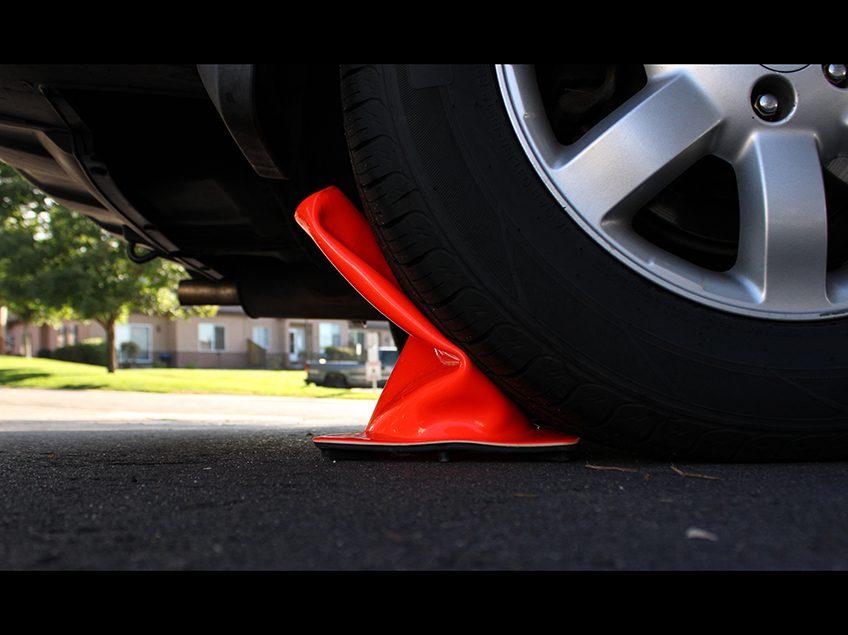汽车轮胎碾压橙色交通锥的特写.
