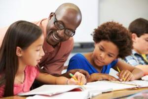 一位非裔美国男教师和两名小学生坐在一张课桌前.