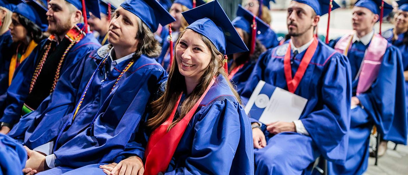 在密歇根州立大学丹佛分校2023春季毕业典礼上，快乐的毕业生坐在观众席中准备接受他们的毕业证书.