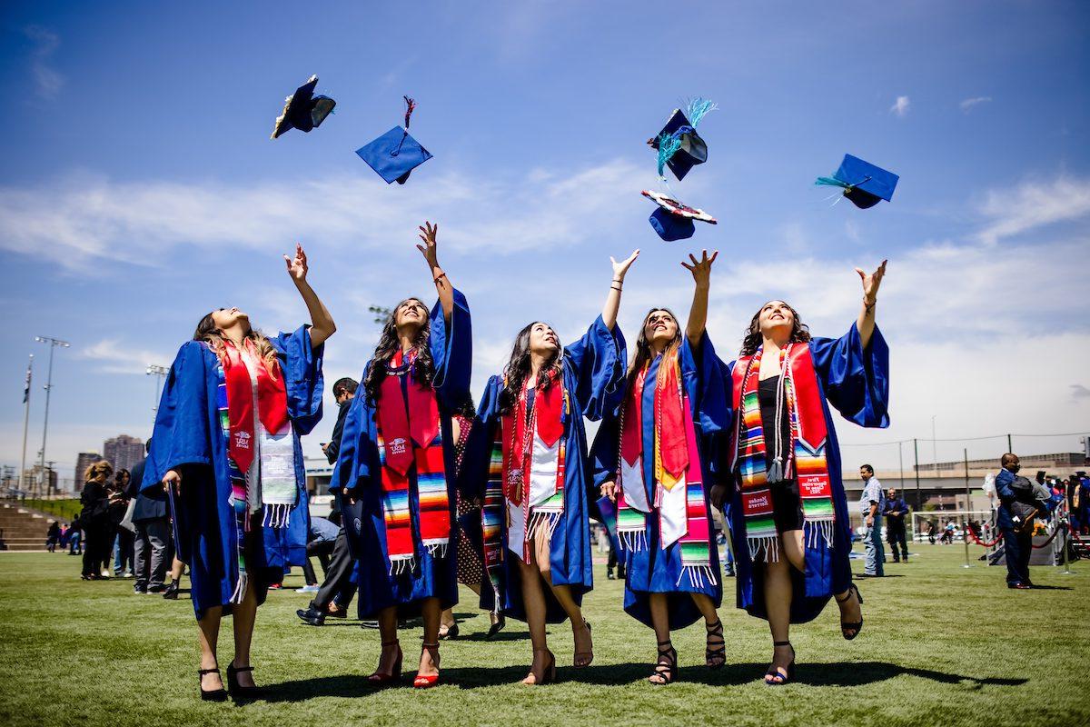 5名密歇根州立大学毕业生在空中抛帽子的照片